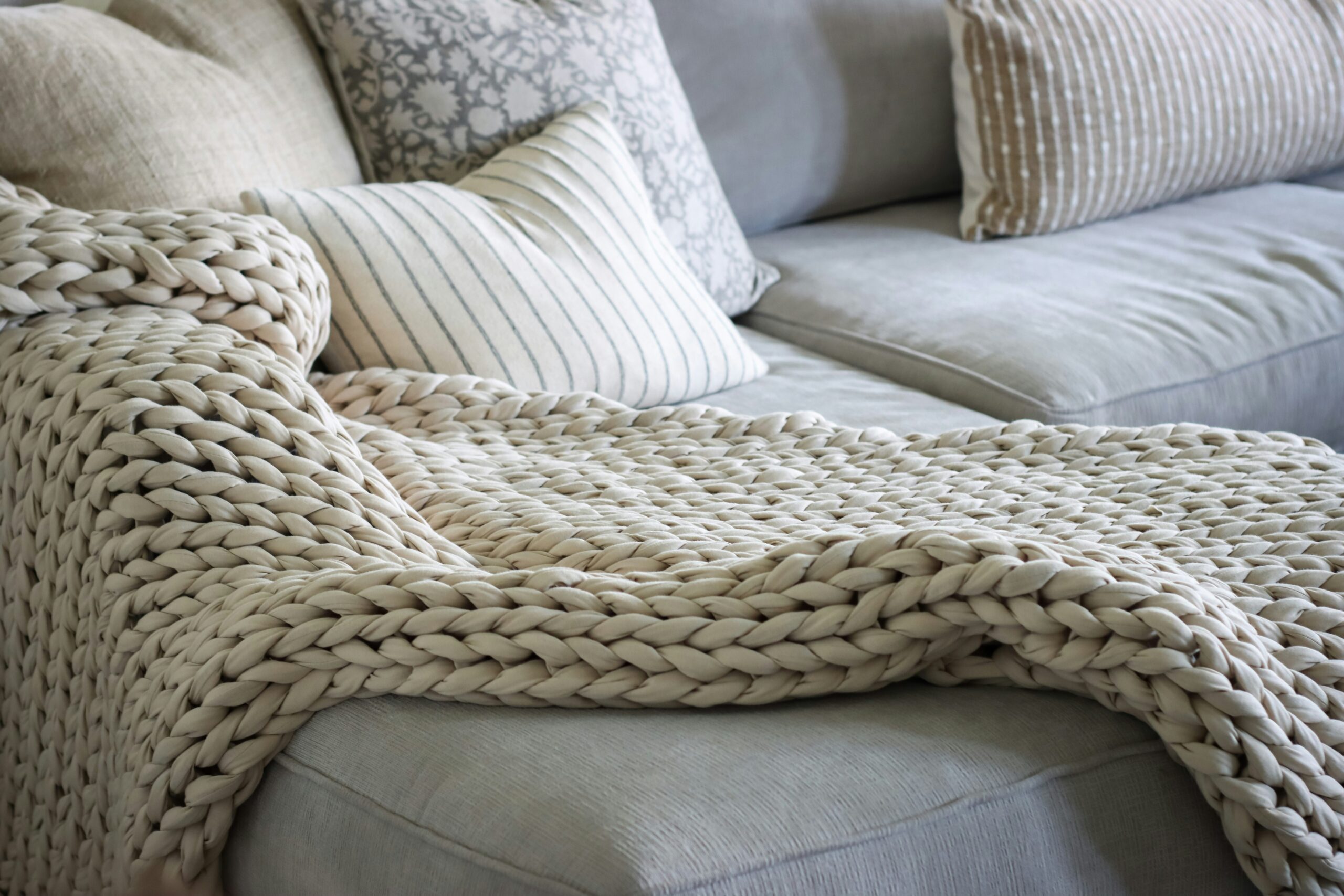 A chunky knit throw blanket styled over furniture, an example of using what you already own