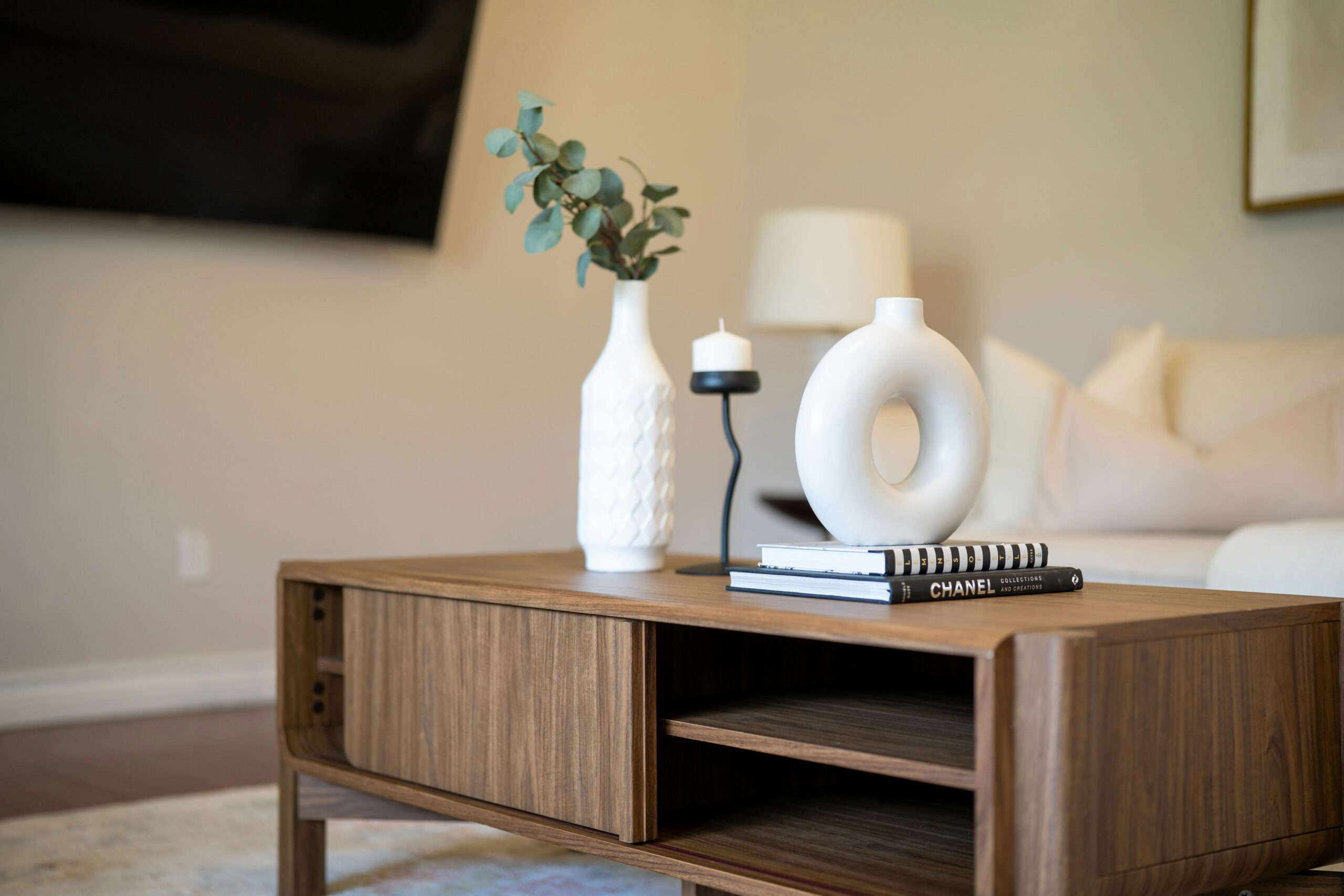 A cozy home on a budget styled with a warm lamp, a lit candle and a small vase, showing soft layered lighting instead of one overhead light