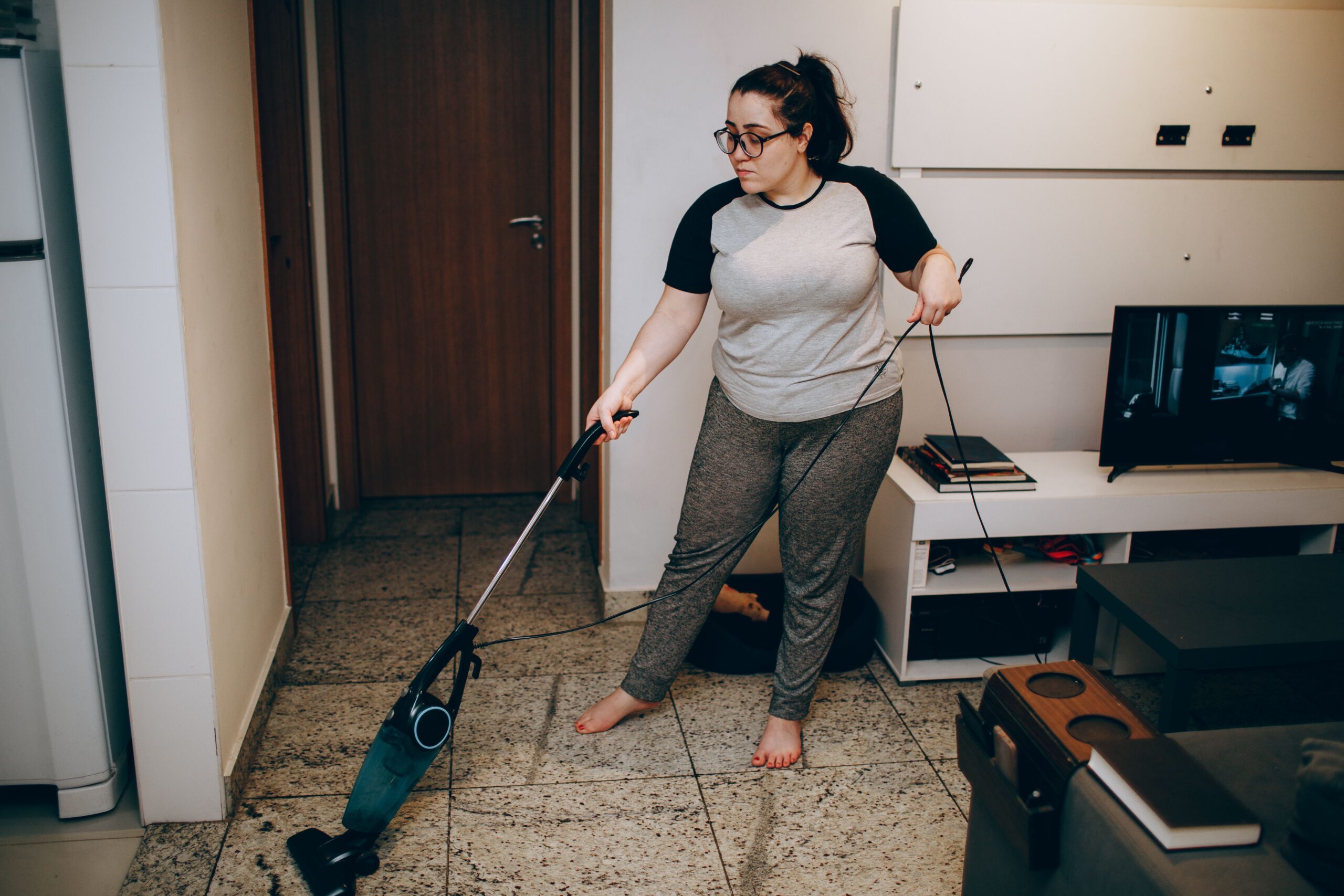 Woman vacuuming a tiled kitchen floor as part of a fall home reset