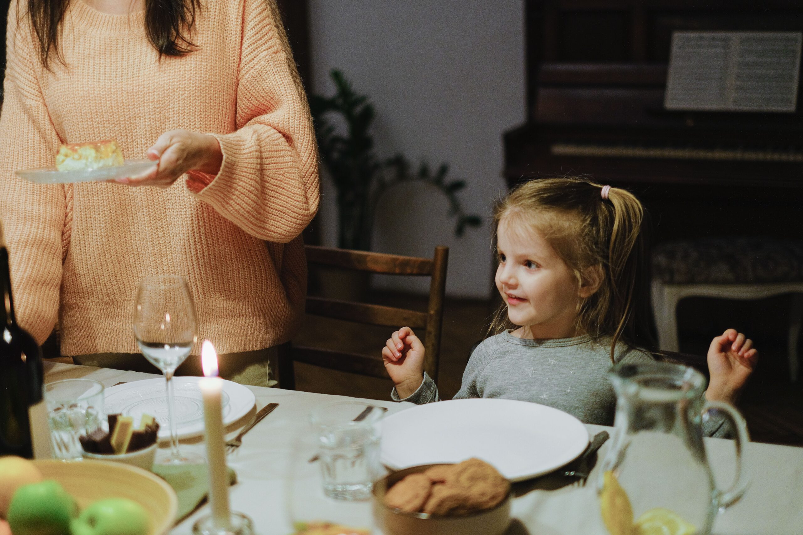 A mom serving a young child at the dinner table by candlelight