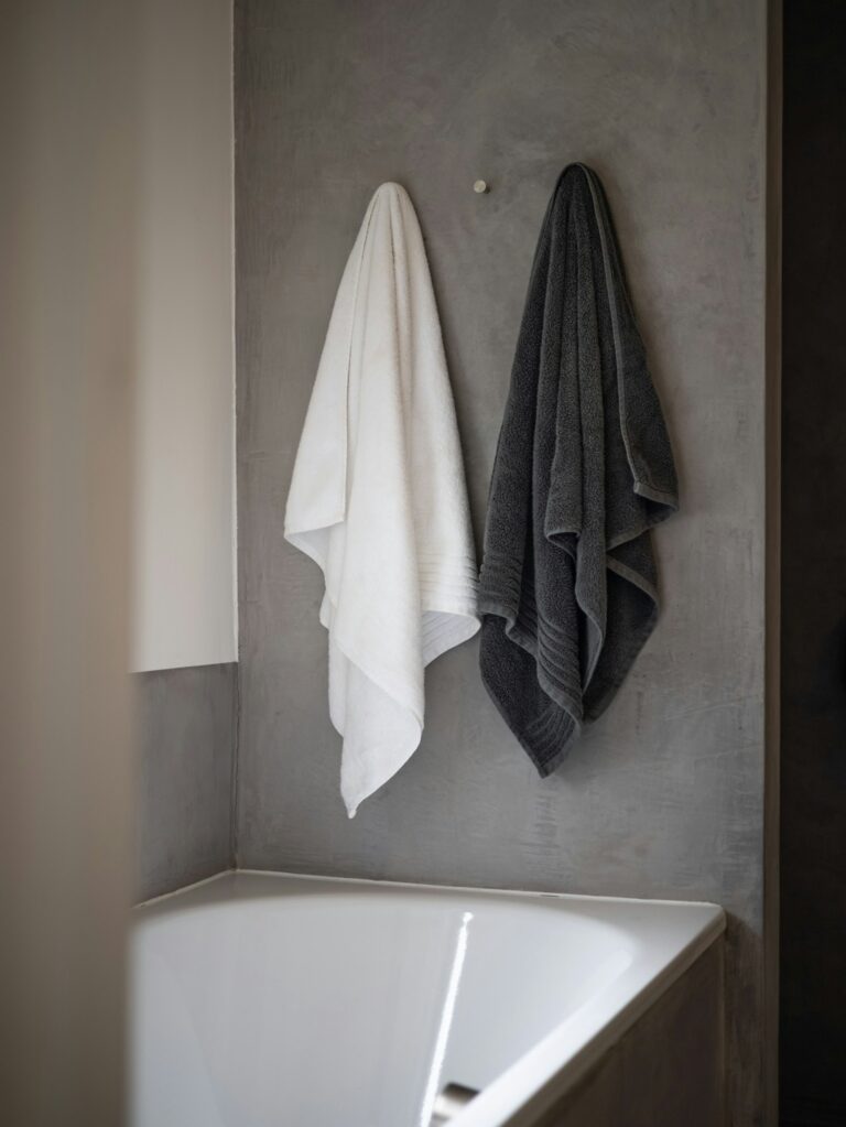 A white bath towel draped on a bathtub