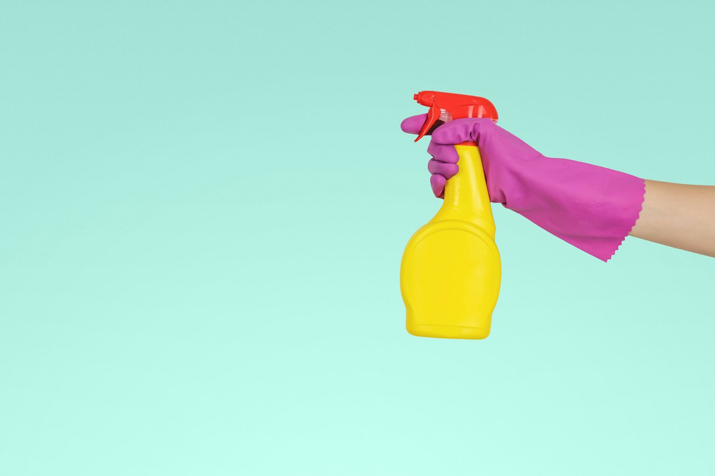 A hand holding a yellow spray bottle