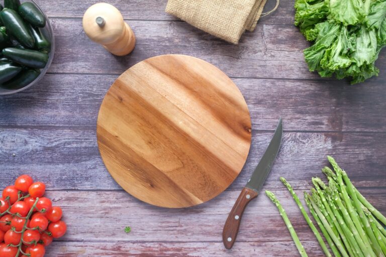 A wooden chopping board beside green vegetables