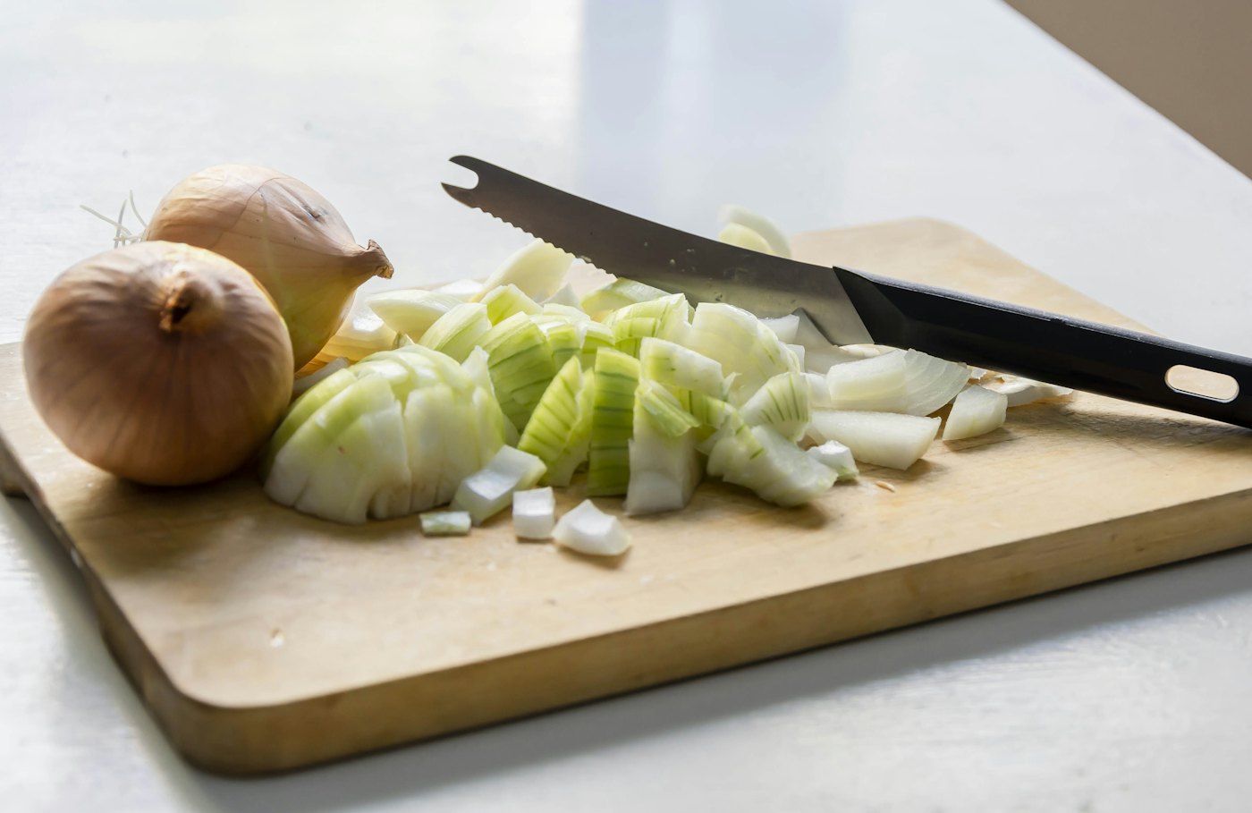 A cutting board with onions and a knife
