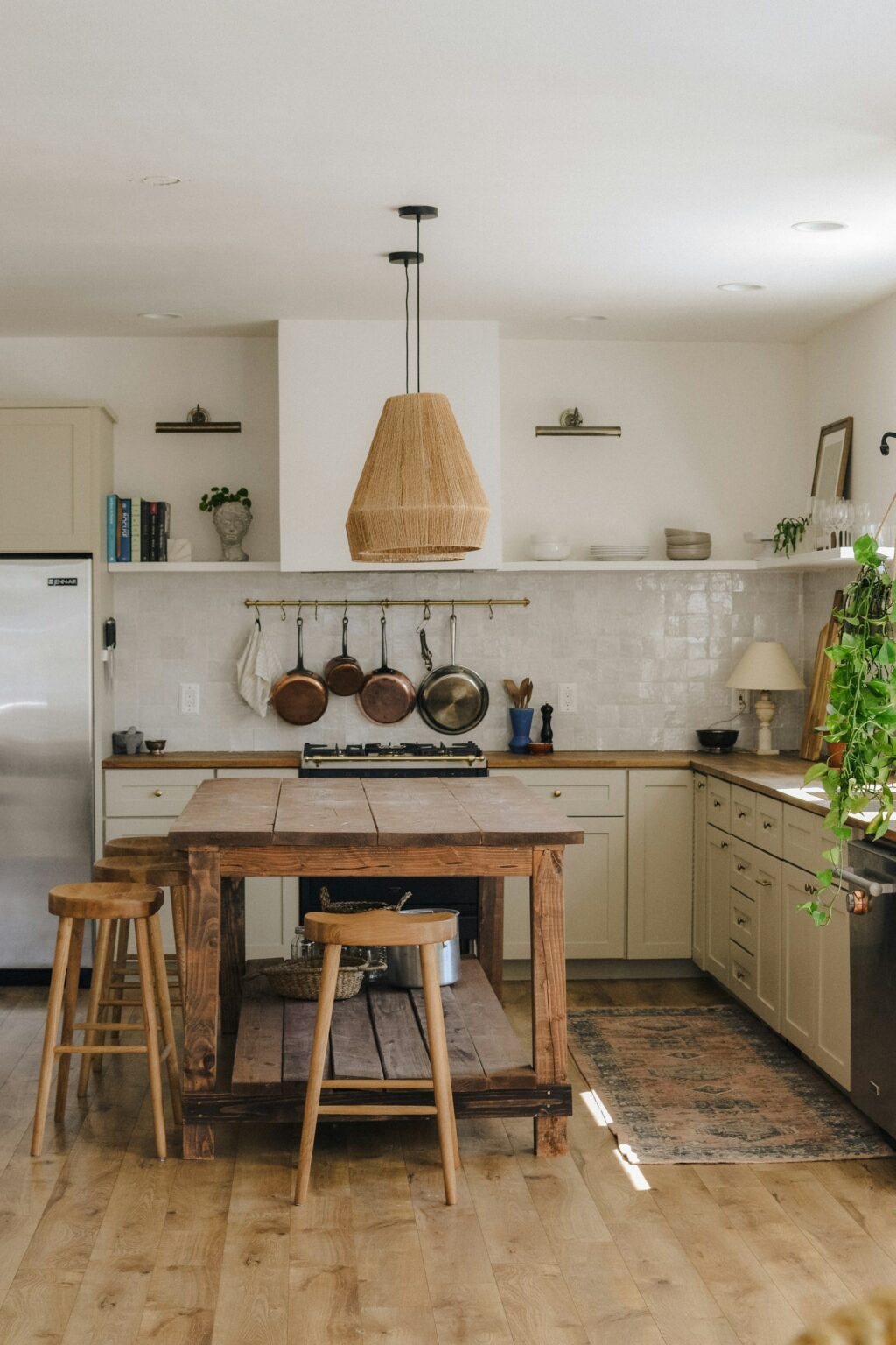 A warm kitchen with a wooden island and stools in natural light