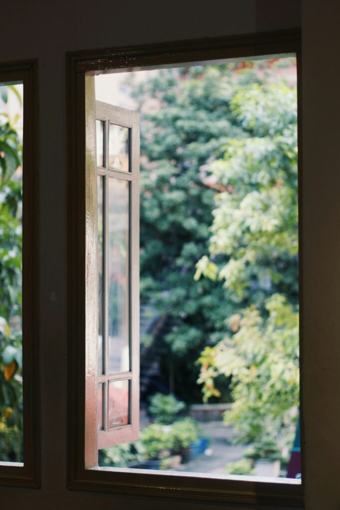 An open window looking out at green trees