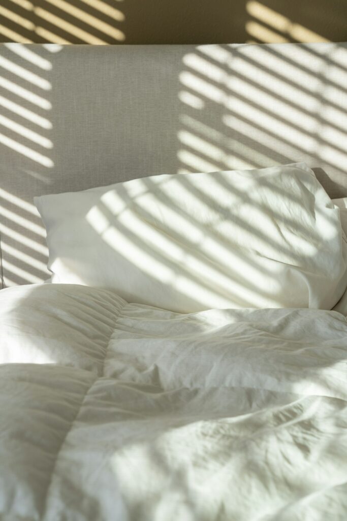 A bed made with white cotton sheets and pillows