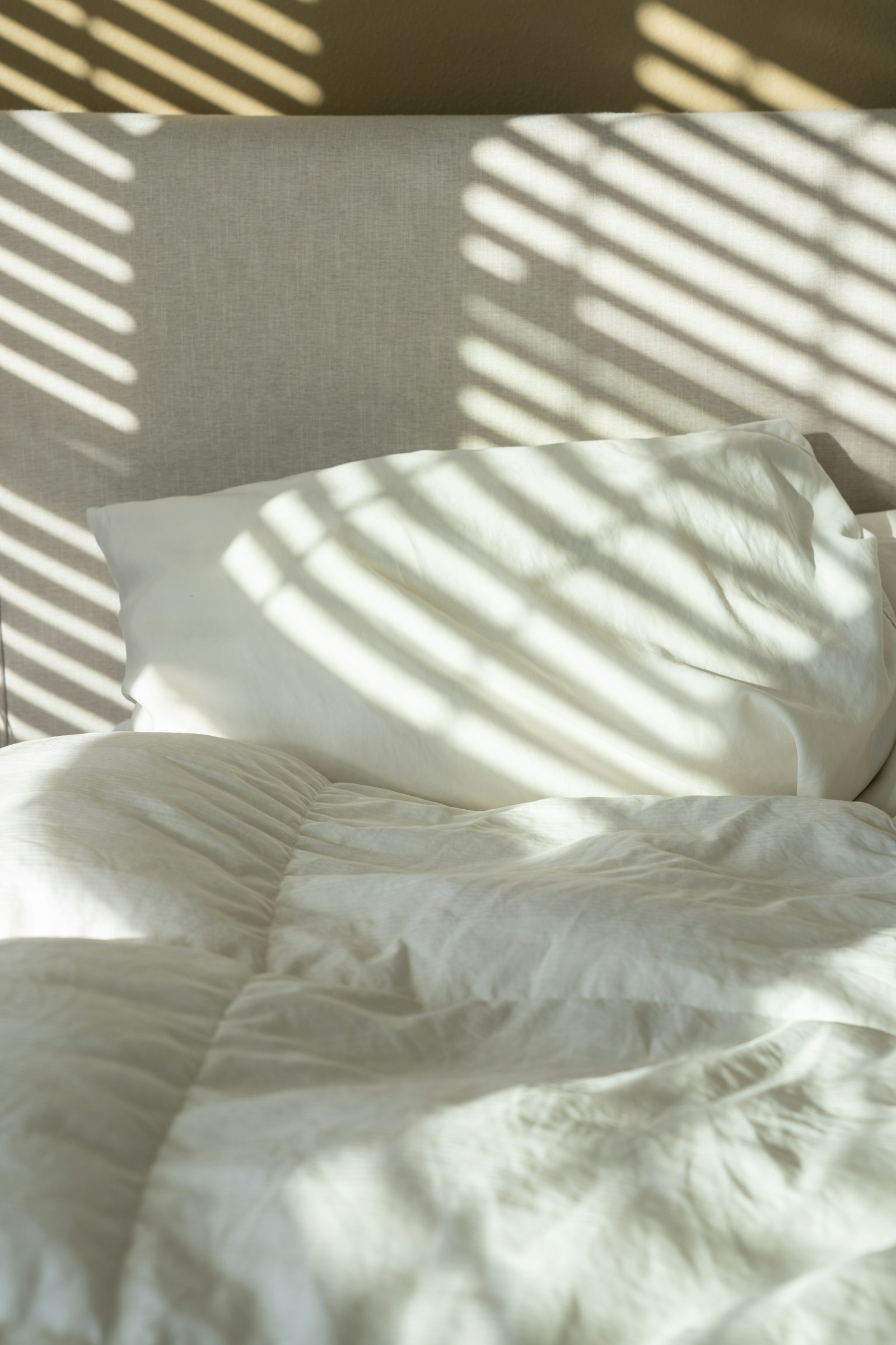 A bed made with white cotton sheets and pillows
