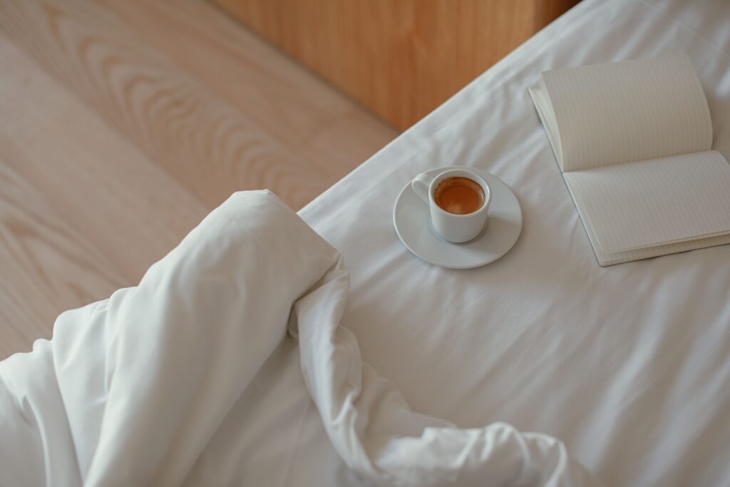 Light comforter on a bed with a cup of tea
