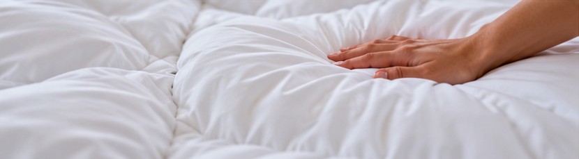 Hand resting on a soft breathable white comforter